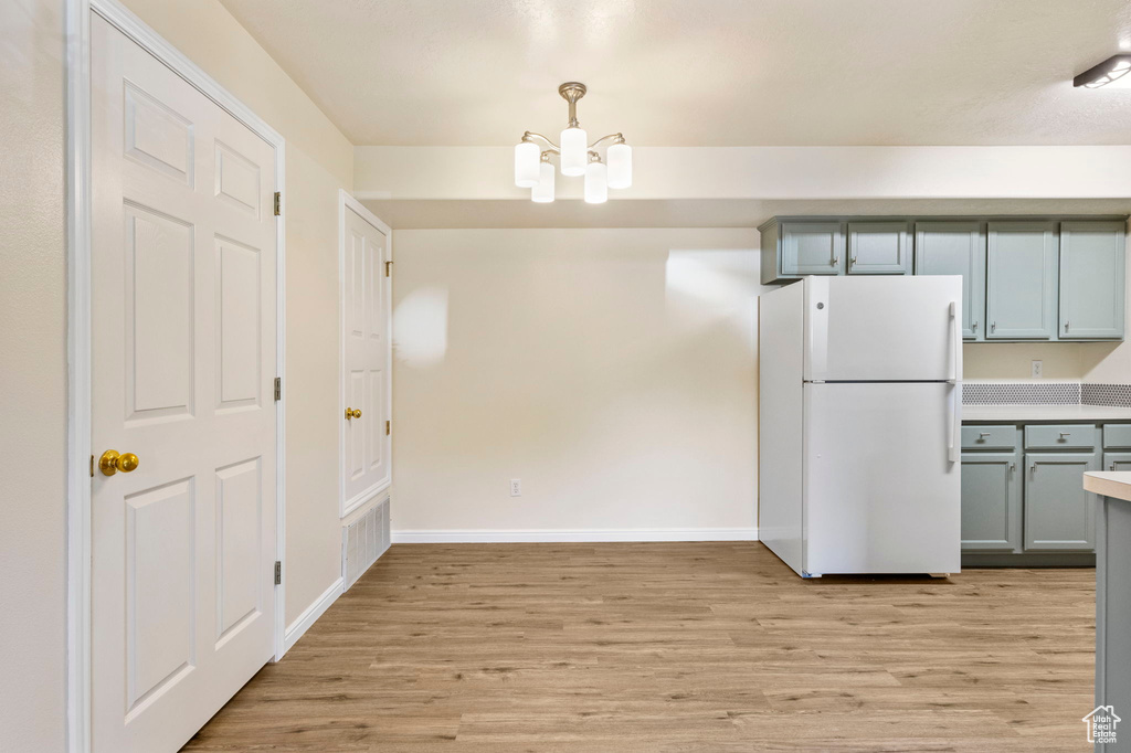 Unfurnished dining area featuring light wood-type flooring, a chandelier, and baseboards