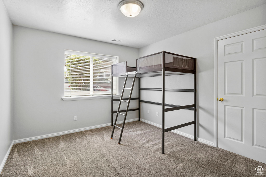 Unfurnished bedroom featuring carpet, baseboards, and a textured ceiling