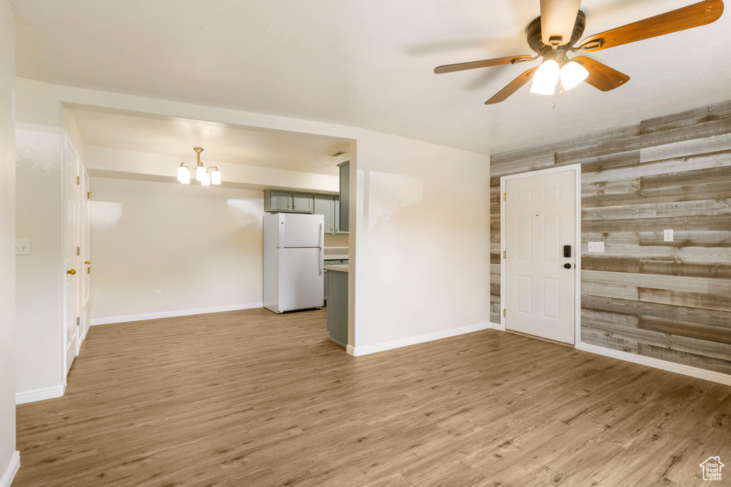 Foyer featuring a ceiling fan, wood finished floors, baseboards, and a chandelier