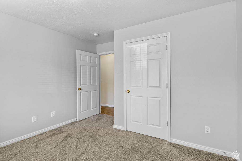 Unfurnished bedroom featuring carpet, baseboards, and a textured ceiling