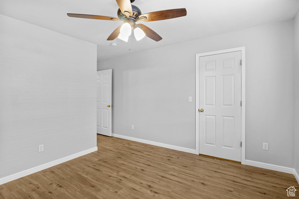 Empty room with wood finished floors, ceiling fan, and baseboards
