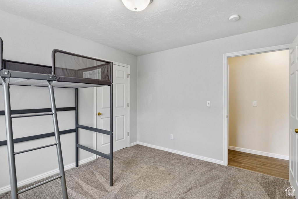 Unfurnished bedroom with carpet flooring, baseboards, and a textured ceiling