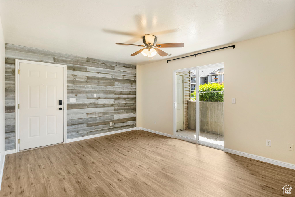 Spare room featuring a ceiling fan, an accent wall, baseboards, and wood finished floors