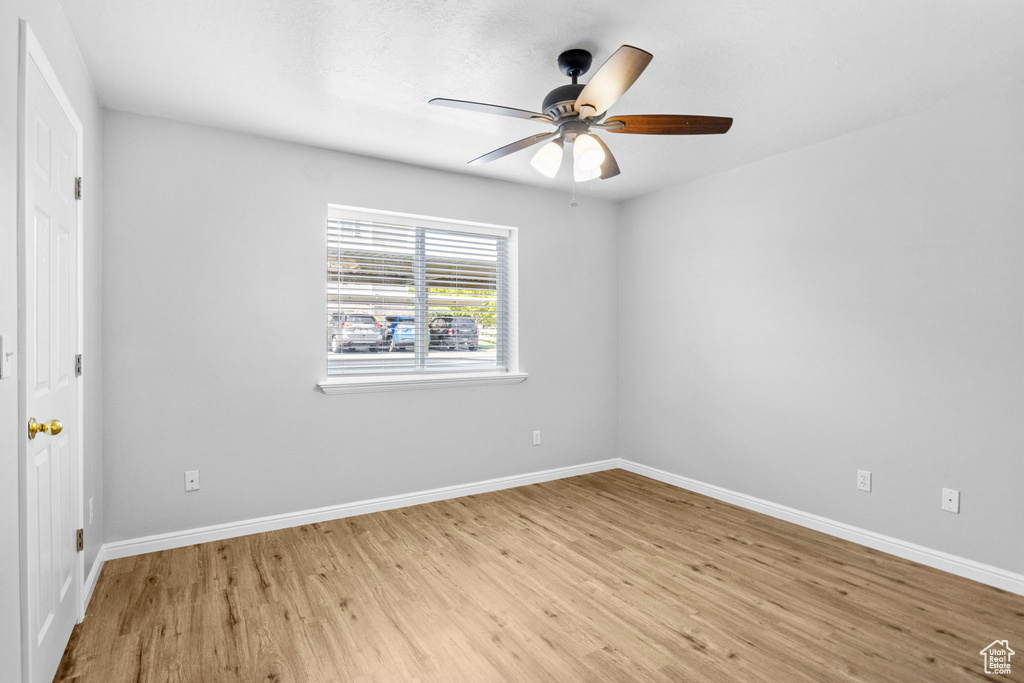 Spare room with light wood-style floors, baseboards, and ceiling fan