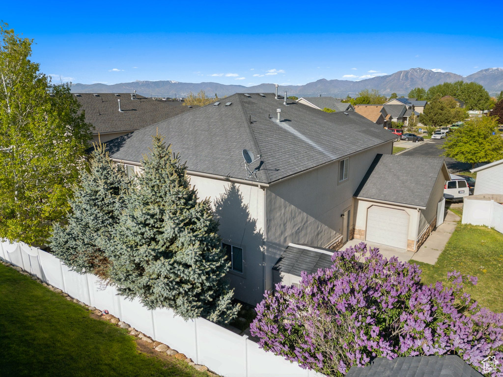 View of home's exterior with a garage, a shingled roof, stucco siding, a mountain view, and a residential view
