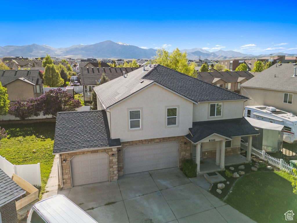 View of front of house with stone siding, an attached garage, stucco siding, and fence