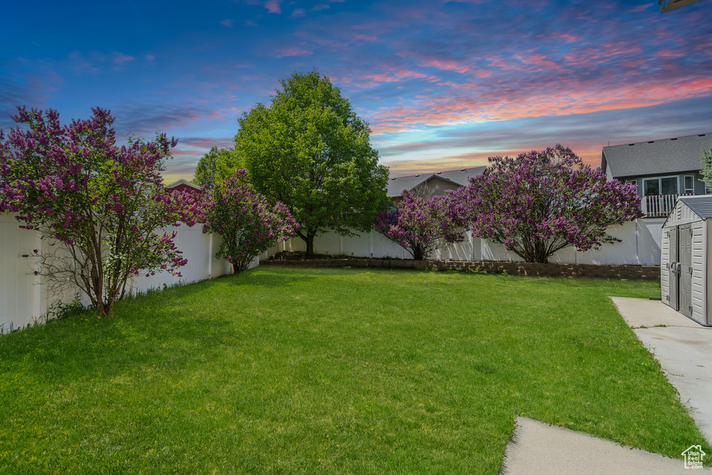 Yard at dusk featuring a shed and an outbuilding