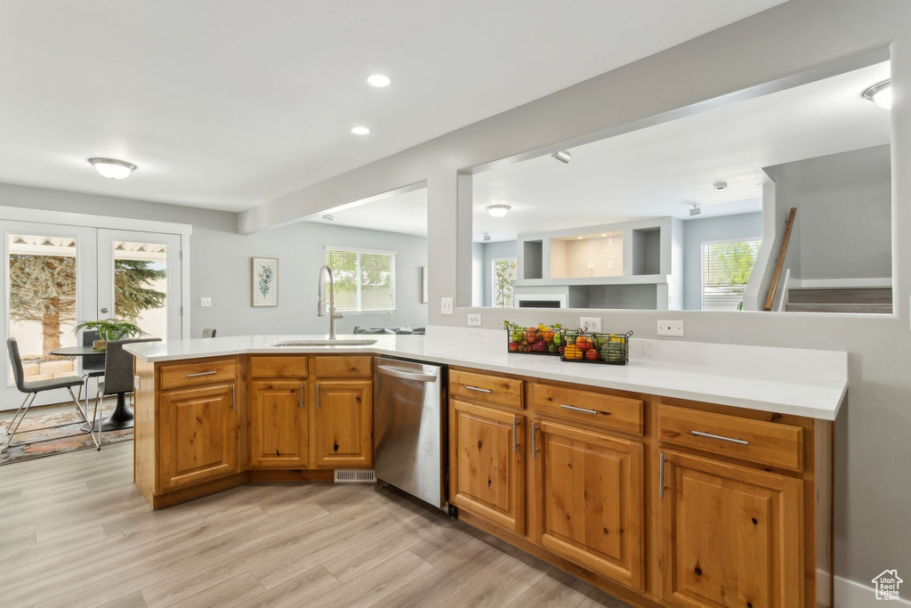 Kitchen with a sink, stainless steel dishwasher, light countertops, light wood-type flooring, and recessed lighting
