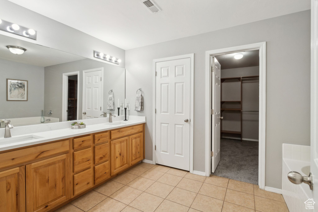 Full bath with a garden tub, tile patterned floors, double vanity, and a spacious closet