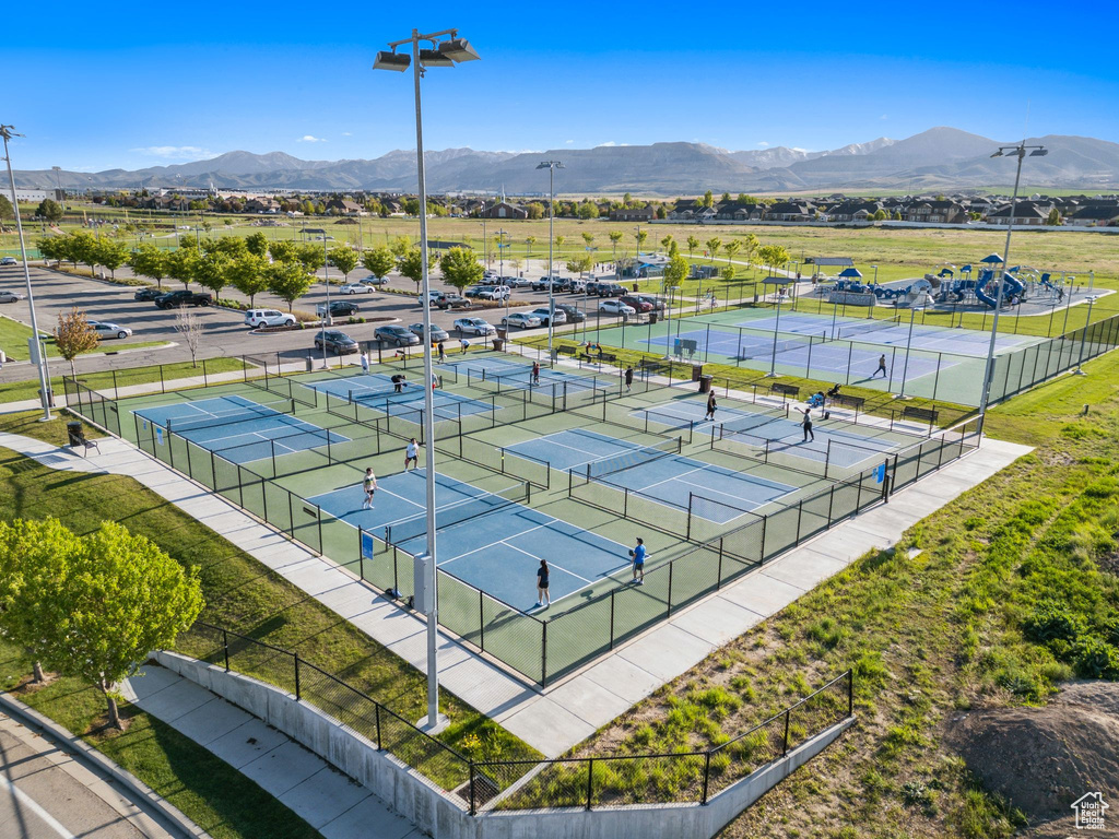 View of tennis court with a mountain view and fence