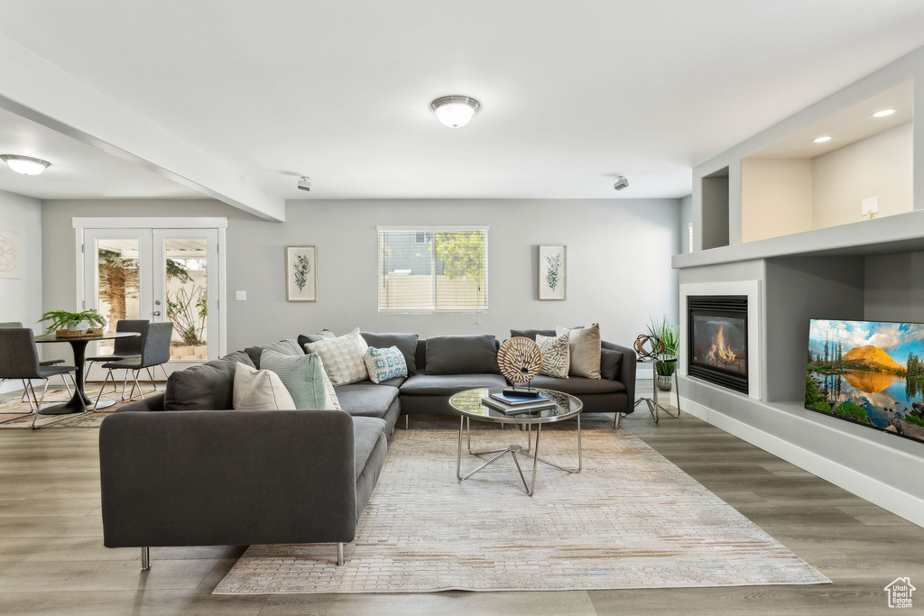 Living area with healthy amount of natural light, a glass covered fireplace, wood finished floors, recessed lighting, and beam ceiling