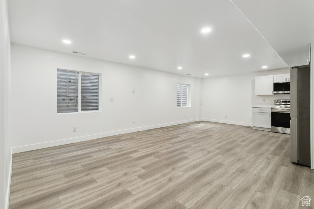 Unfurnished living room featuring recessed lighting, light wood finished floors, and baseboards