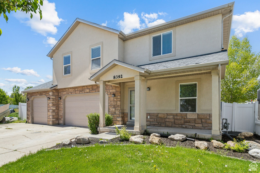 View of front facade with stone siding, an attached garage, stucco siding, and driveway