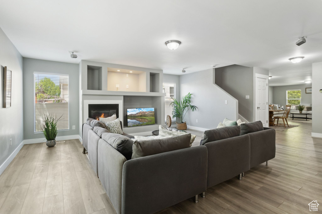 Living area featuring light wood-type flooring, baseboards, and a glass covered fireplace