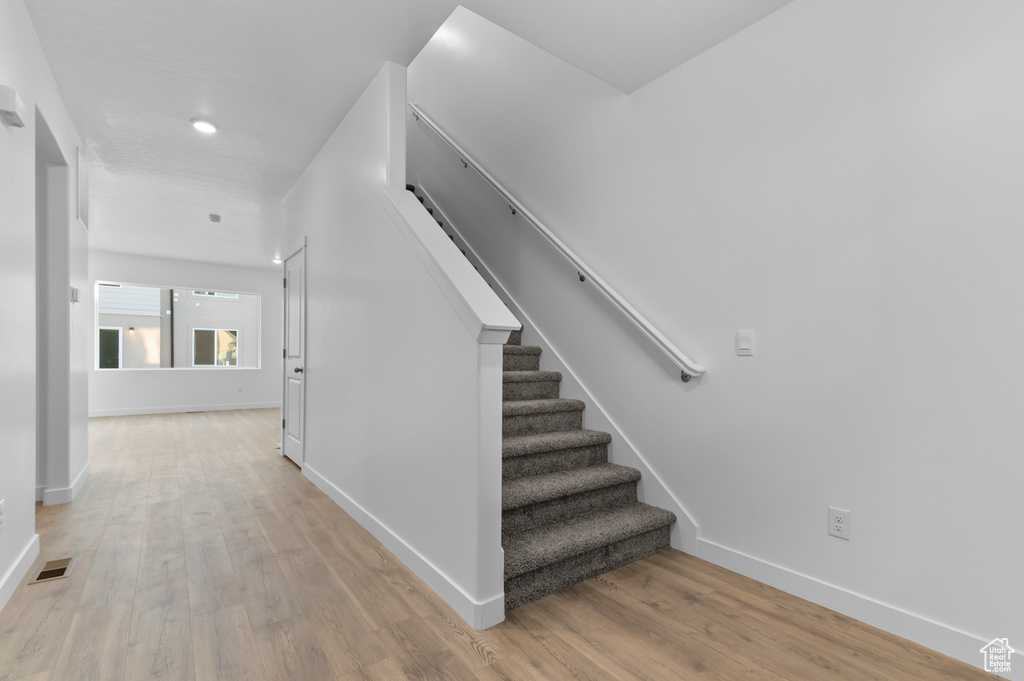 Staircase with wood finished floors, baseboards, and recessed lighting