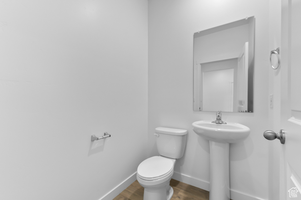 Bathroom with wood finished floors, toilet, and baseboards