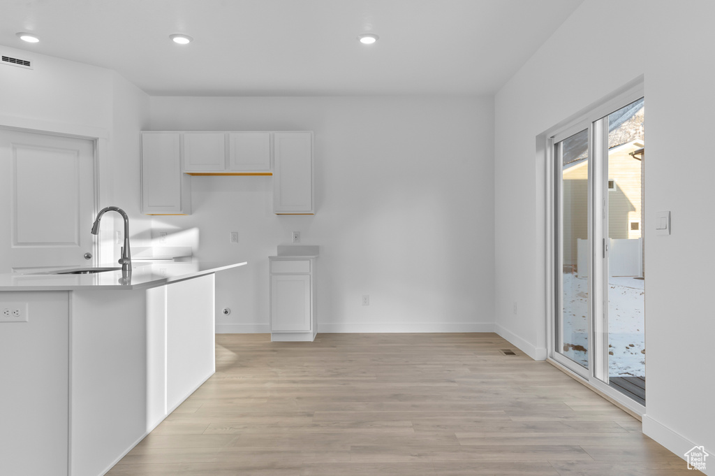Kitchen with a sink, healthy amount of natural light, recessed lighting, light wood-style flooring, and white cabinetry