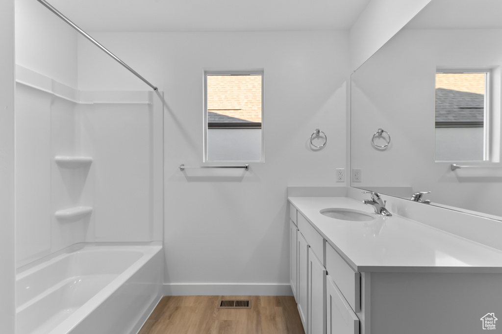 Full bath featuring healthy amount of natural light, baseboards, wood finished floors, and vanity