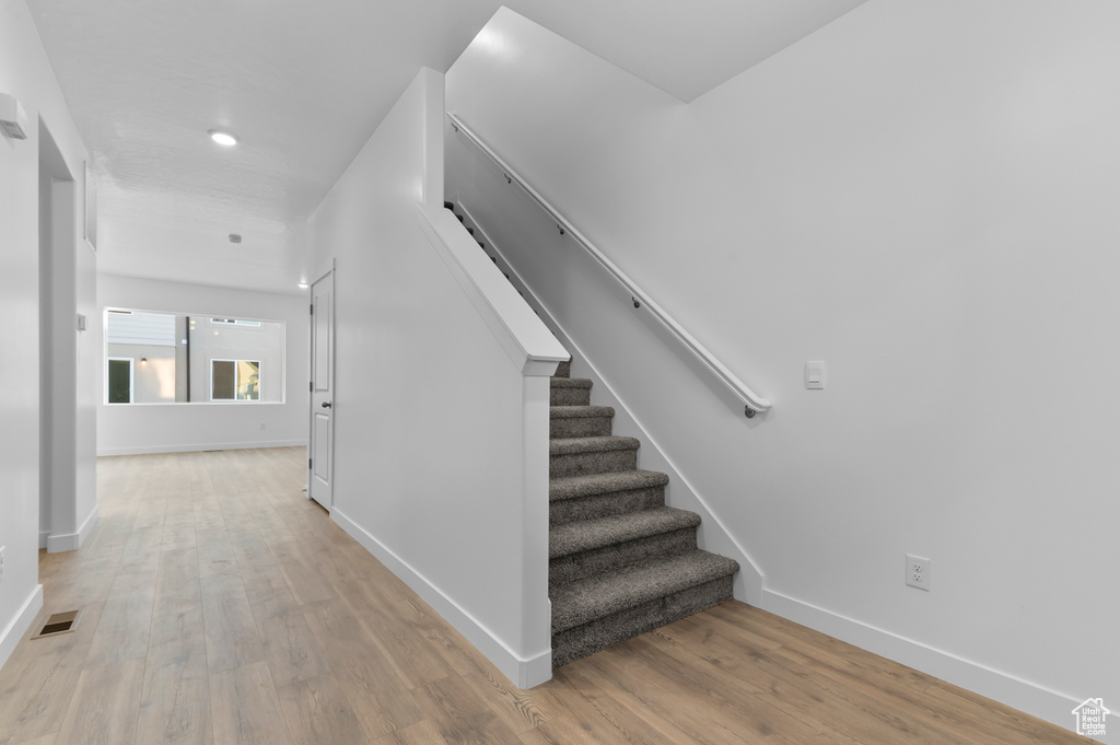 Stairway with wood finished floors, baseboards, and recessed lighting