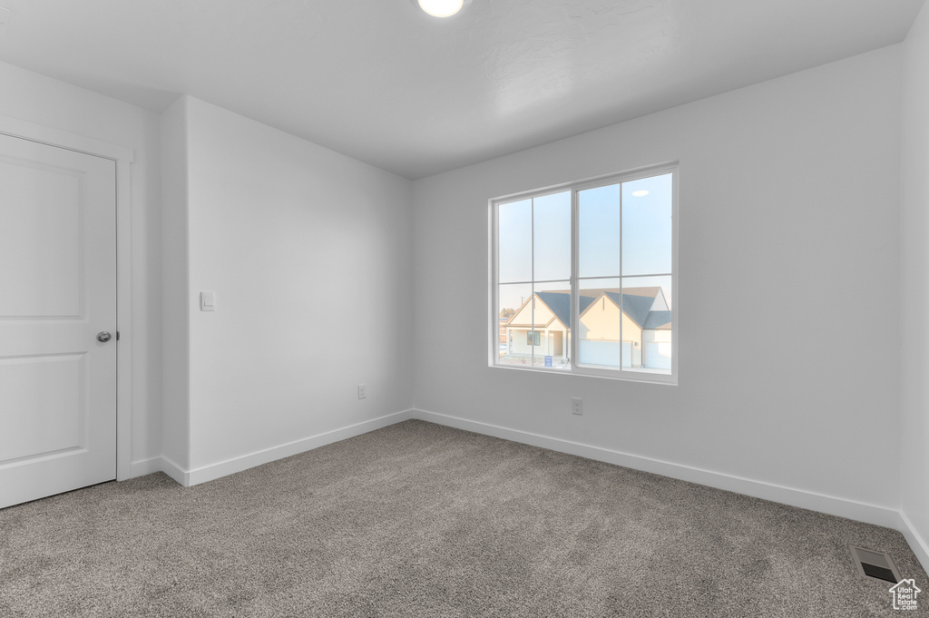 Carpeted spare room featuring baseboards