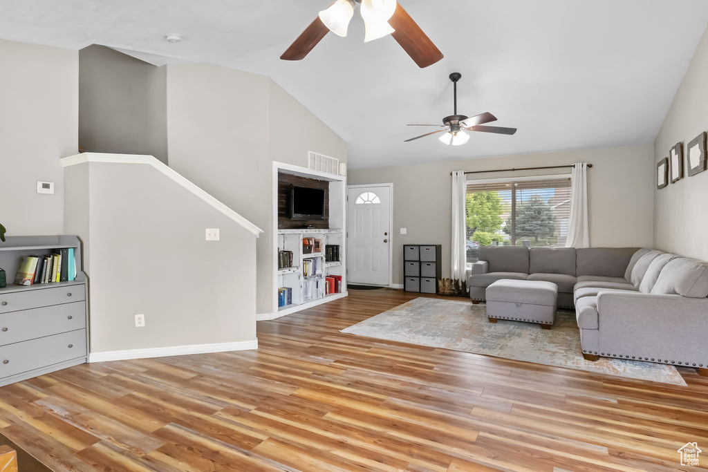 Living area with ceiling fan, wood finished floors, high vaulted ceiling, and baseboards