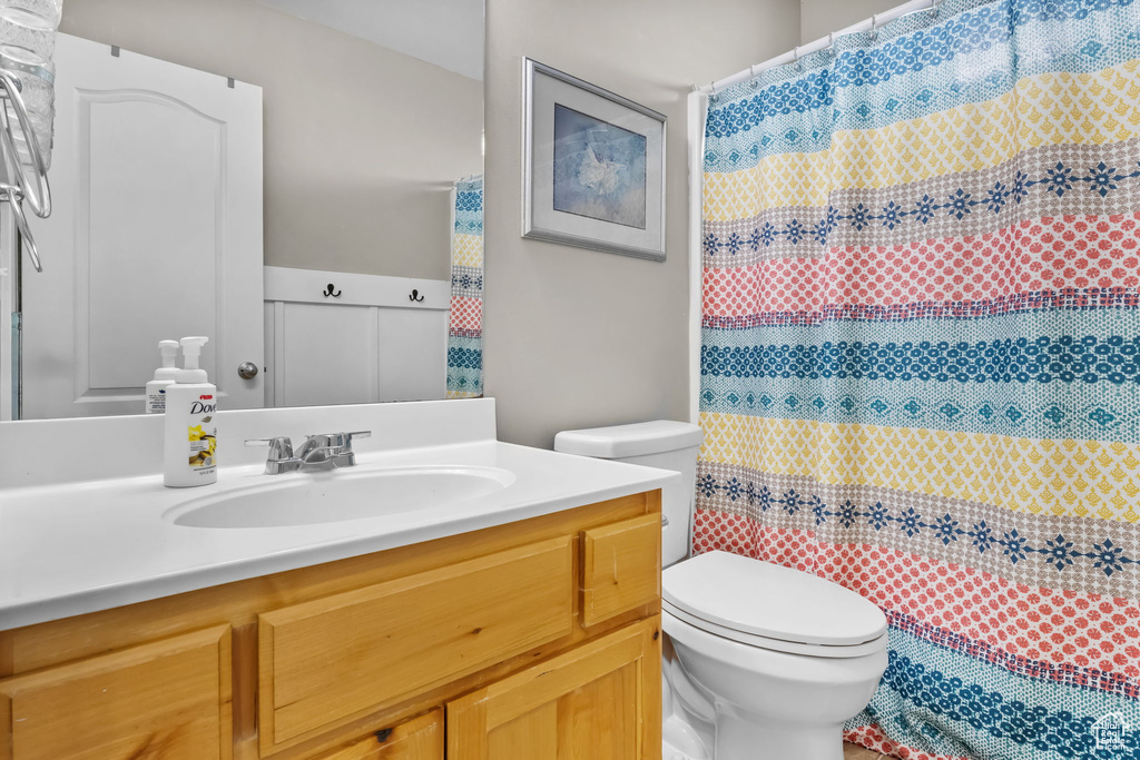 Bathroom with toilet, vanity, and a shower with curtain