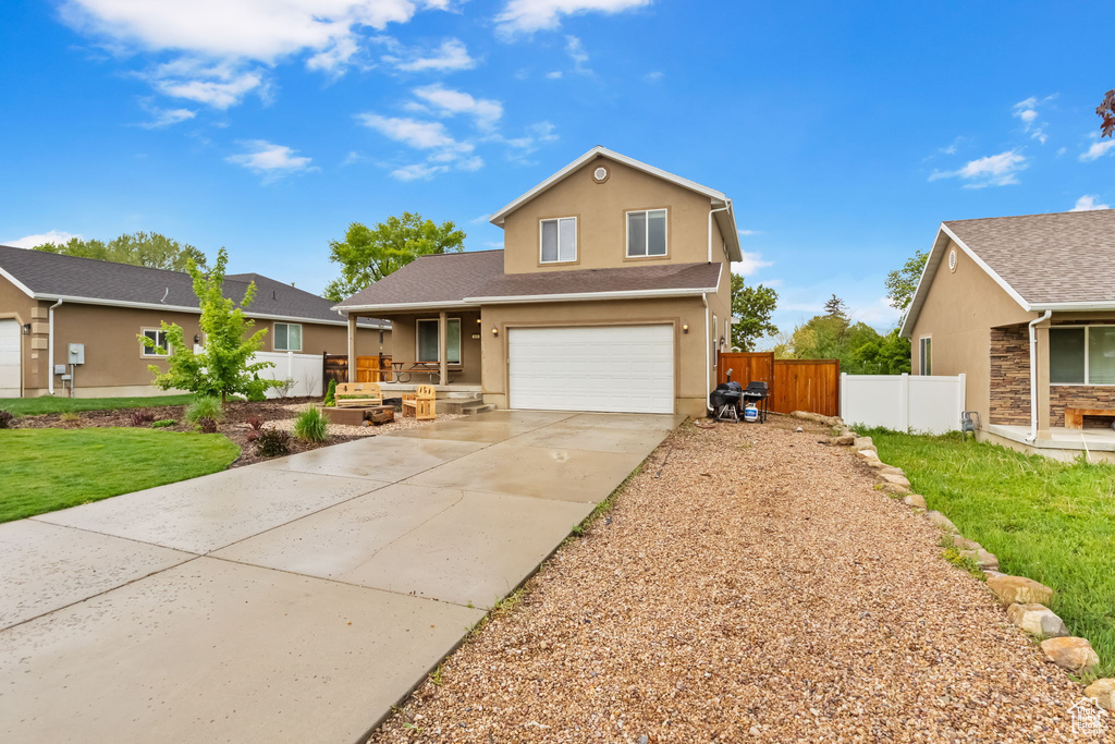 Traditional-style house featuring a garage, concrete driveway, stucco siding, and a porch