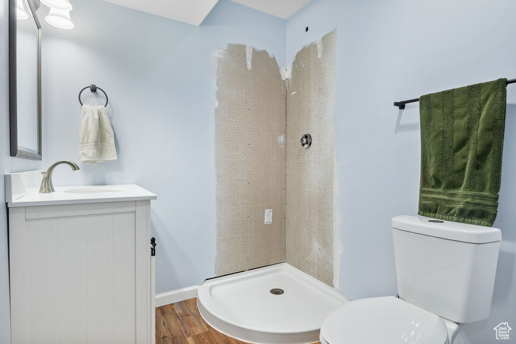 Full bath featuring toilet, a shower stall, vanity, and wood finished floors