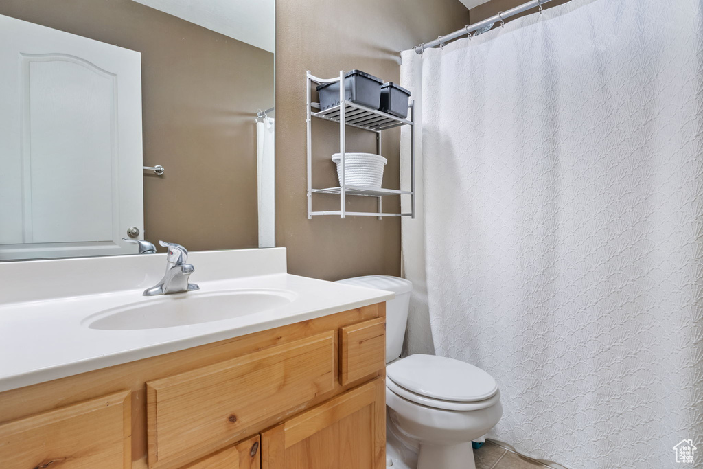Full bath with toilet, vanity, tile patterned floors, and a shower with shower curtain