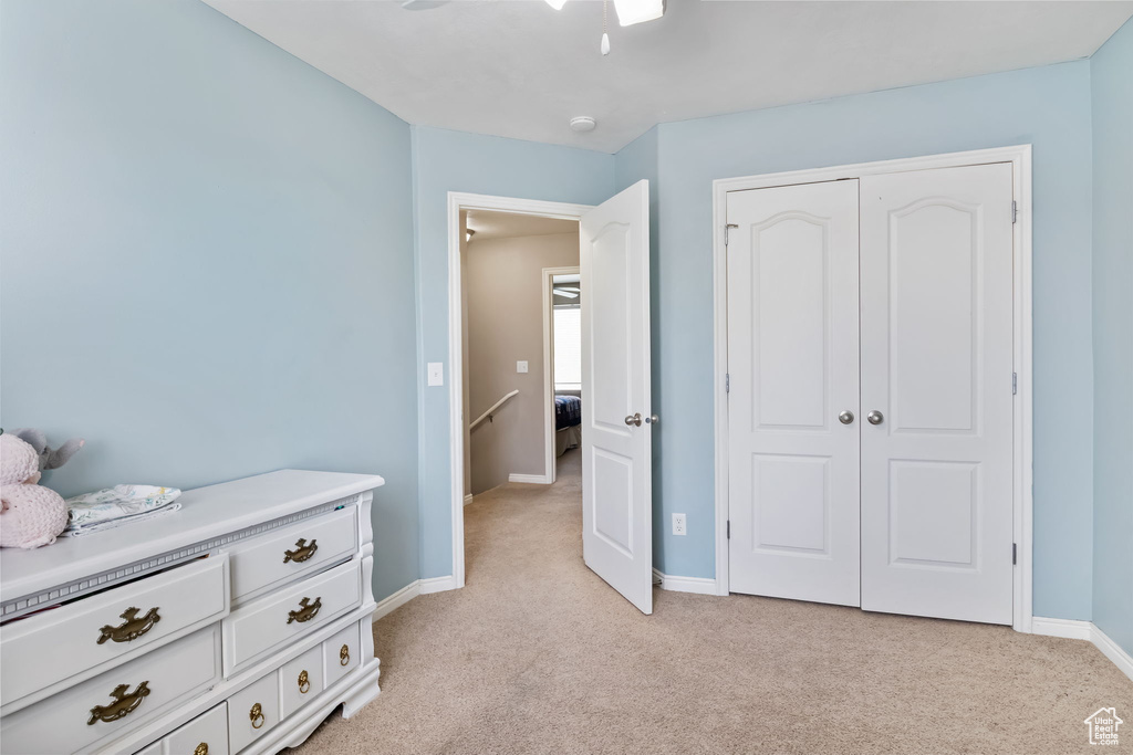 Bedroom featuring light carpet, baseboards, a closet, and ceiling fan