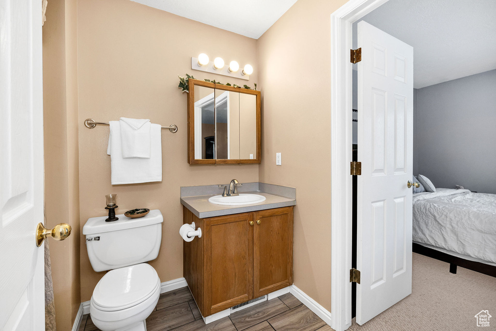 Bathroom with vanity, toilet, baseboards, and ensuite bath