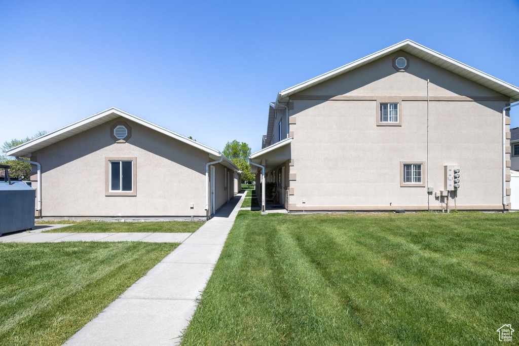 Back of house with a yard and stucco siding