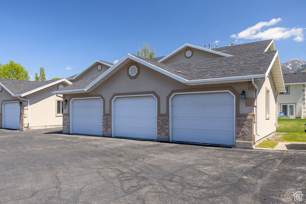 View of front facade with stucco siding and a shingled roof