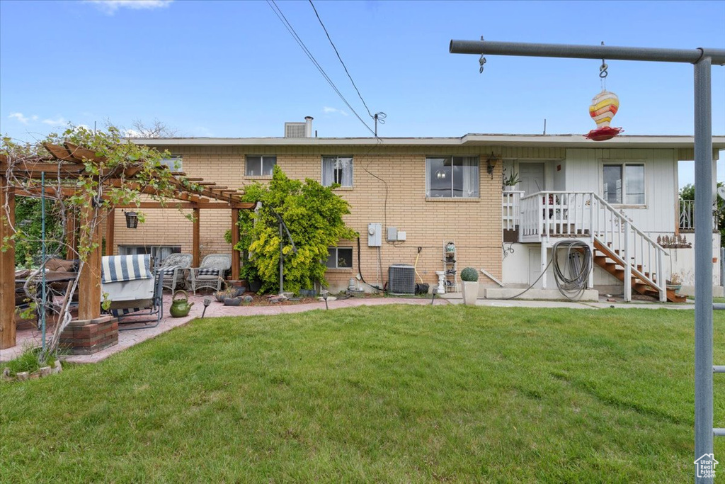 Rear view of property featuring brick siding, a yard, a pergola, and a patio area