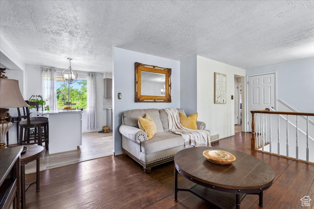 Living area with a textured ceiling, a chandelier, hardwood / wood-style floors, and baseboards