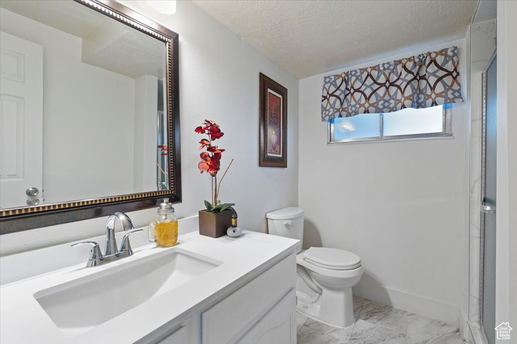 Bathroom featuring marble finish floors, toilet, a textured ceiling, and vanity