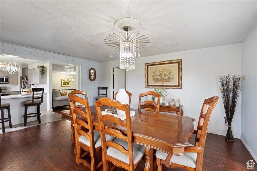 Dining area with a chandelier, wood-type flooring, and baseboards