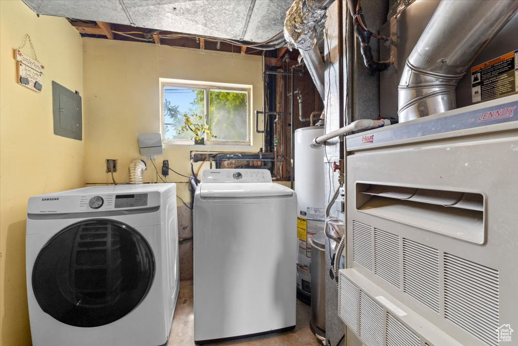 Laundry area featuring washing machine and clothes dryer, heating unit, electric panel, and water heater