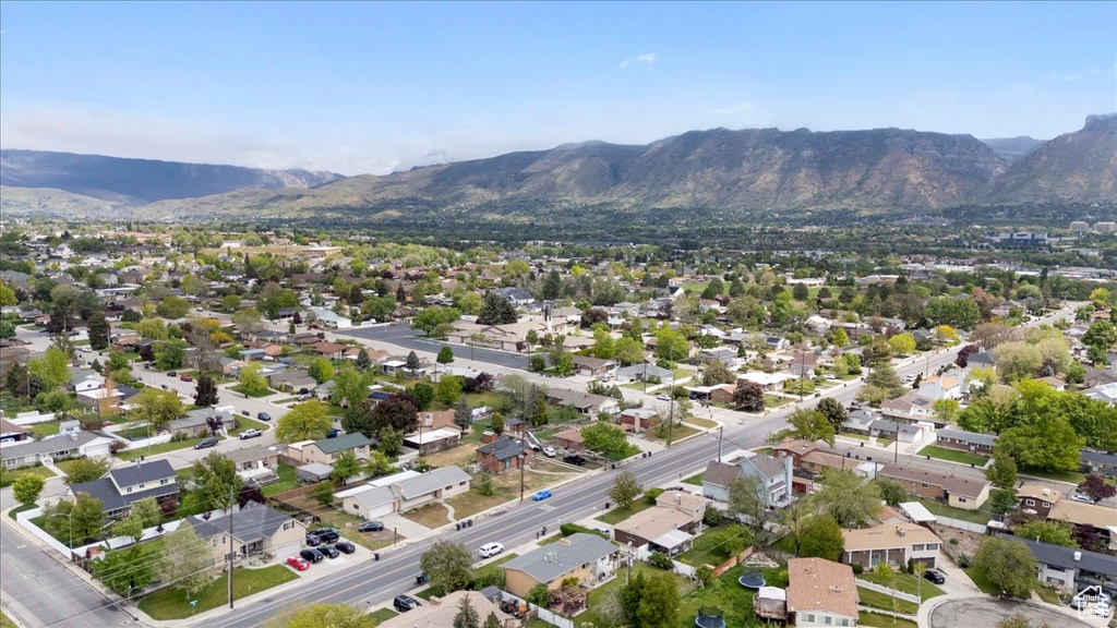 Aerial view of property and surrounding area featuring mountains and nearby suburban area