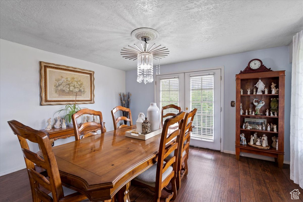 Dining space with a chandelier, dark wood-style flooring, a textured ceiling, and baseboards