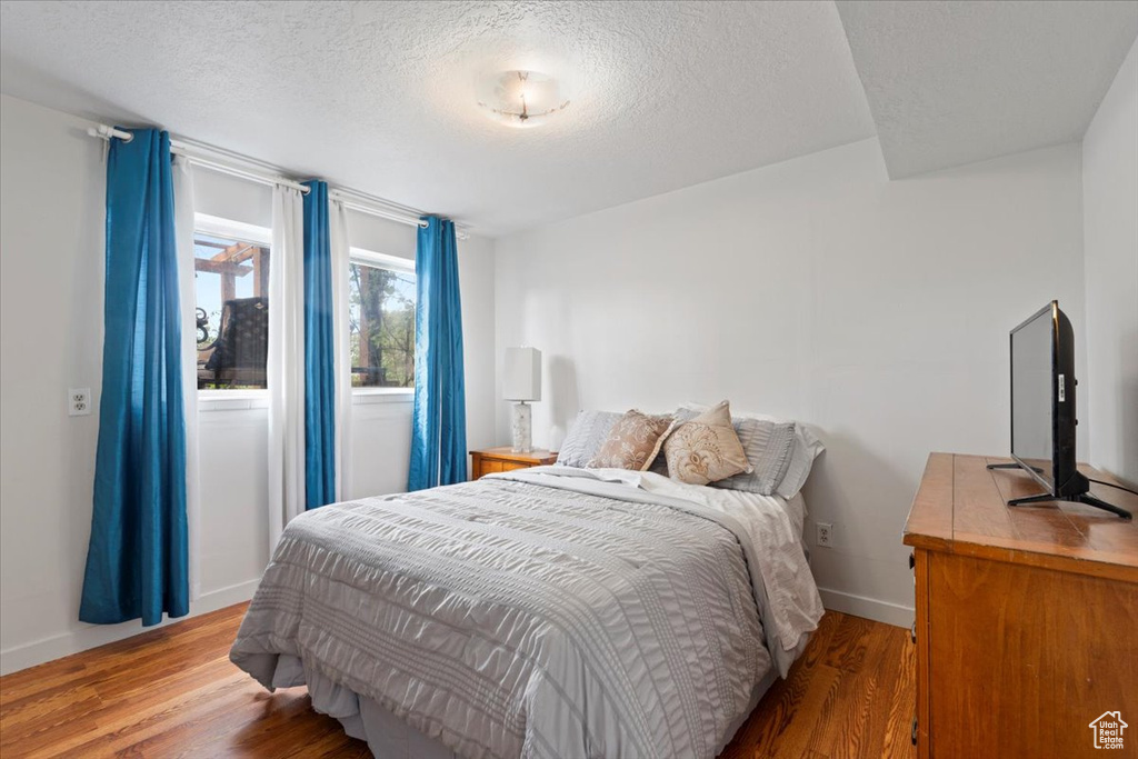 Bedroom featuring wood finished floors, a textured ceiling, and baseboards
