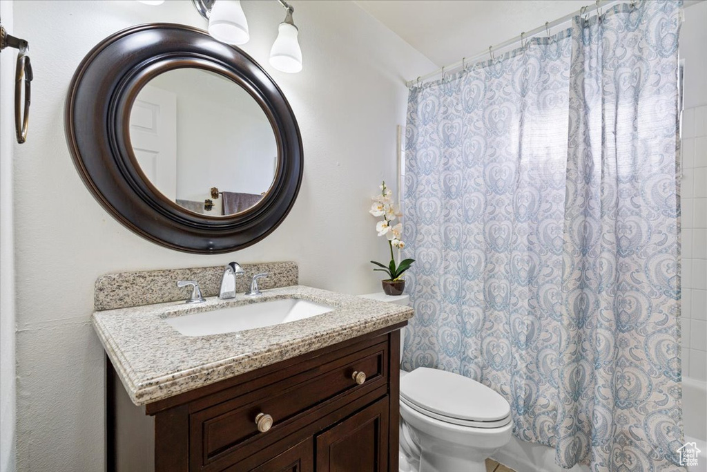 Bathroom with toilet, vanity, and shower / tub combo with curtain