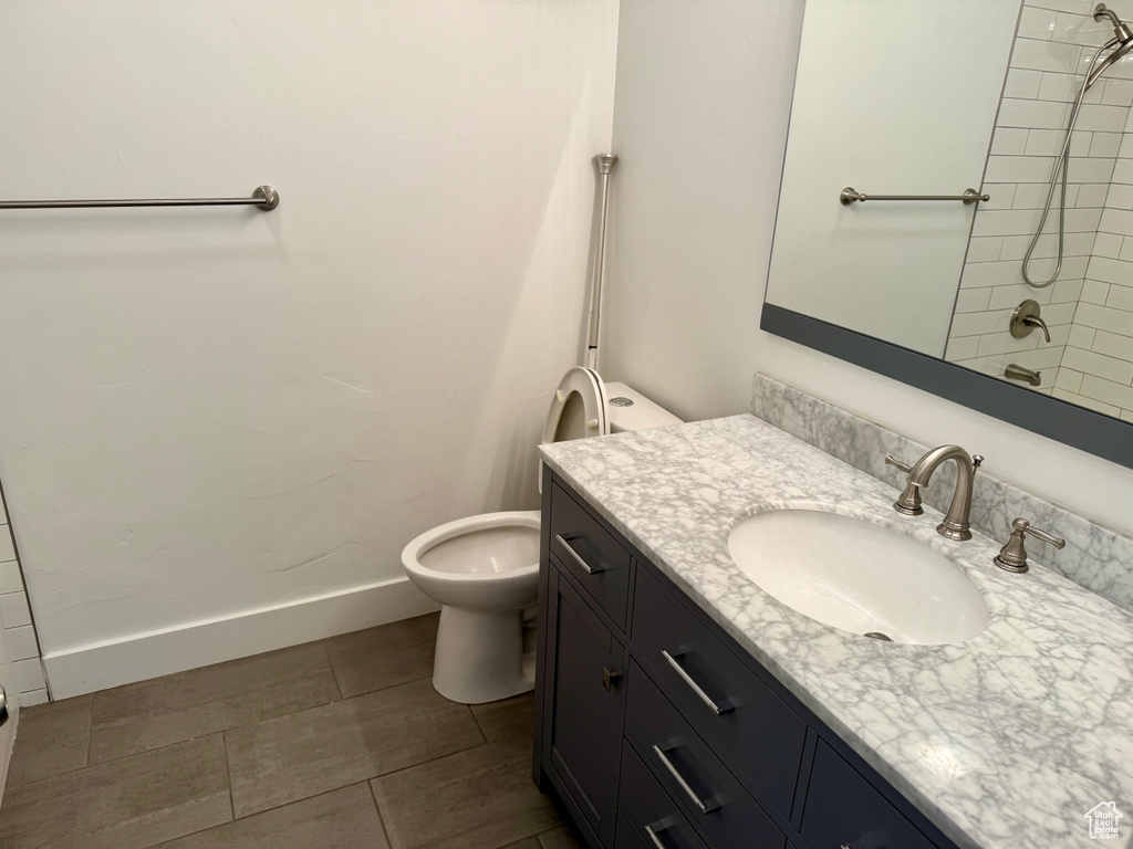 Bathroom with vanity, a shower, toilet, and baseboards