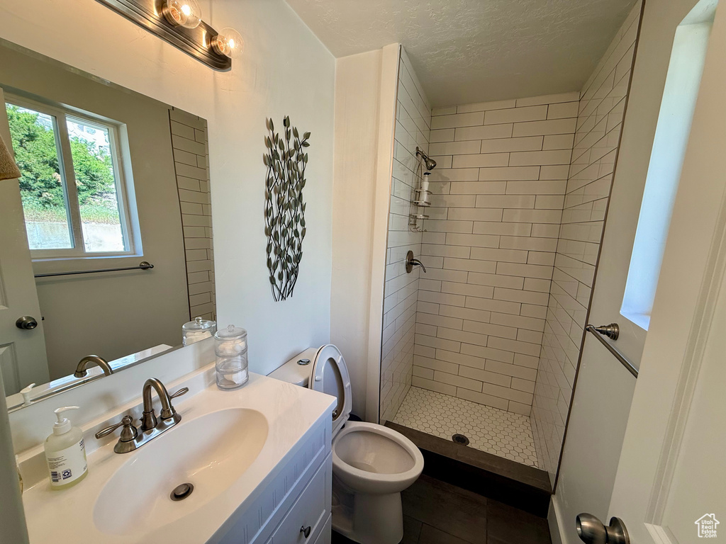 Bathroom featuring a stall shower, tile patterned floors, vanity, toilet, and a textured ceiling