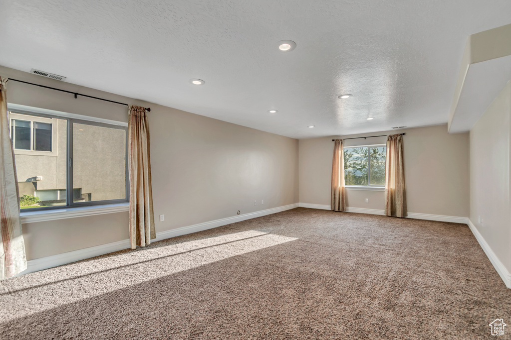 Unfurnished room featuring a textured ceiling, carpet, baseboards, and recessed lighting
