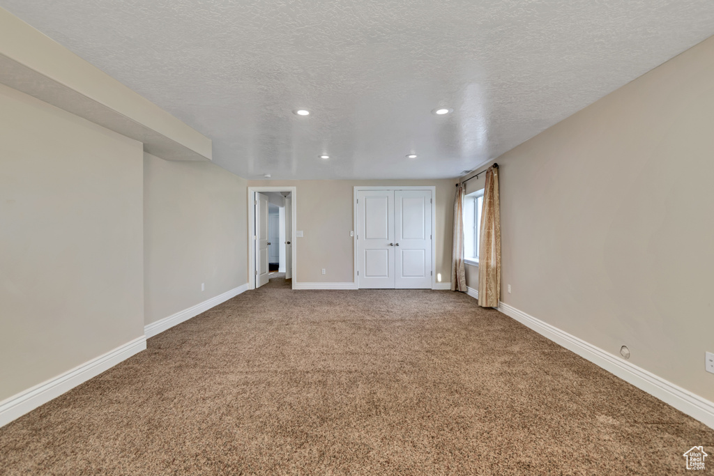 Carpeted spare room featuring recessed lighting, a textured ceiling, and baseboards