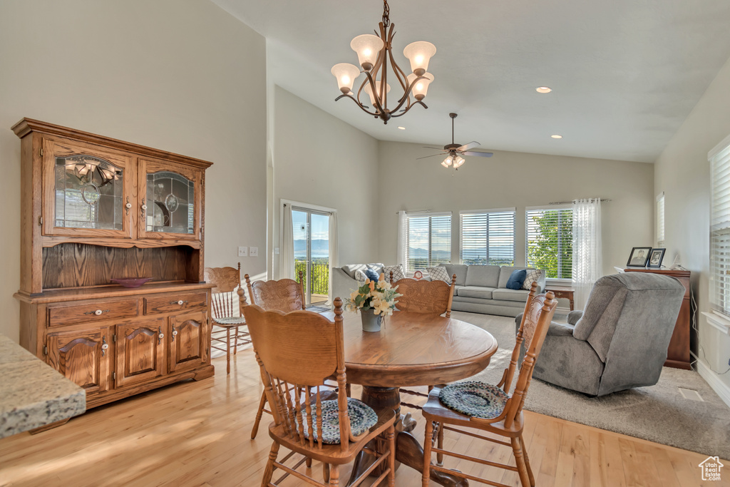 Dining area featuring light wood finished floors, ceiling fan, a chandelier, recessed lighting, and high vaulted ceiling