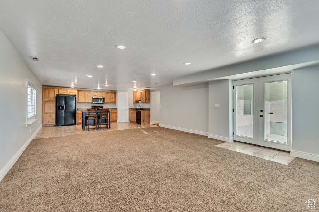 Unfurnished living room with light colored carpet, recessed lighting, baseboards, french doors, and a textured ceiling