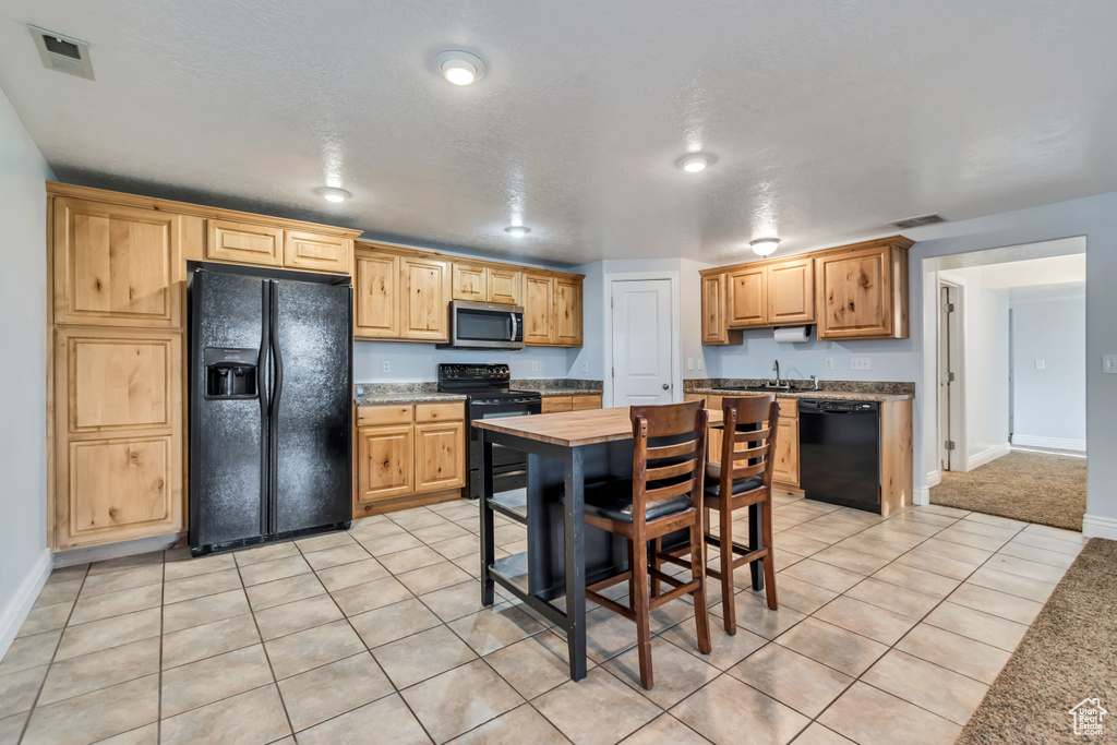 Kitchen with black appliances, baseboards, a sink, and light tile patterned floors