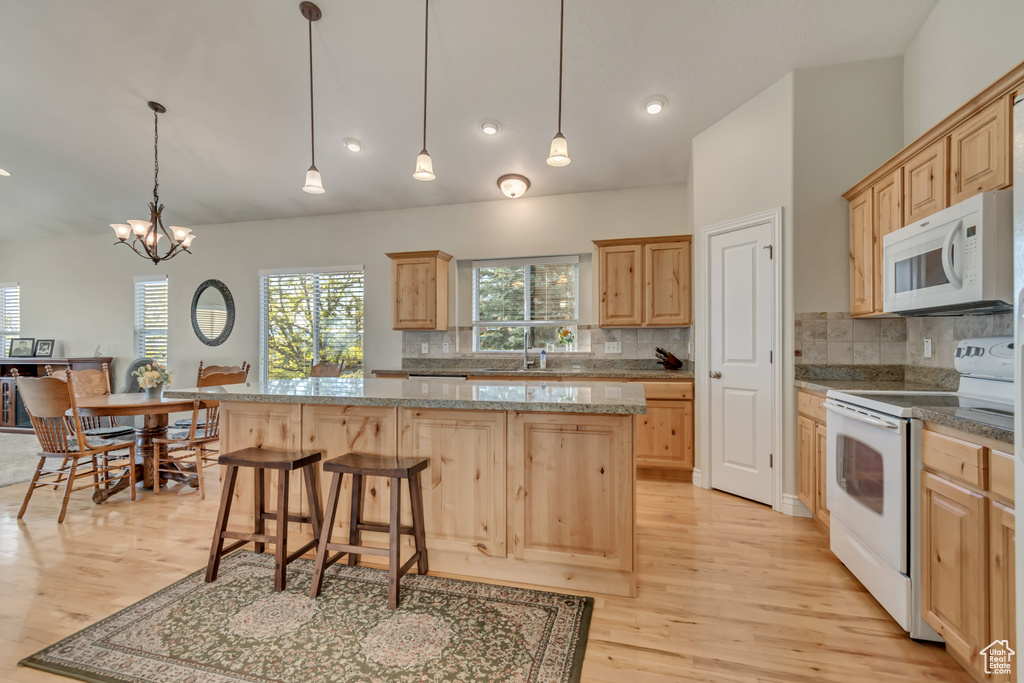 Kitchen featuring white appliances, light brown cabinets, light wood-style floors, a center island, and recessed lighting